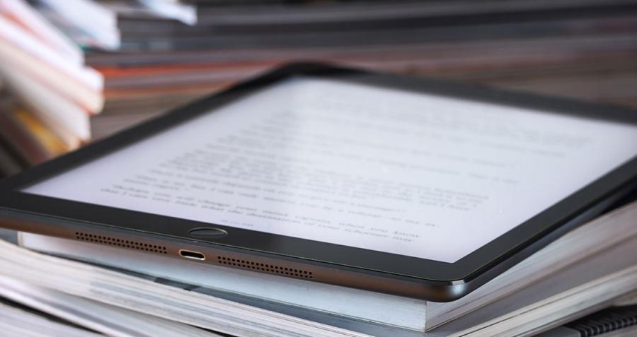 Tablet on pile of books with glasses