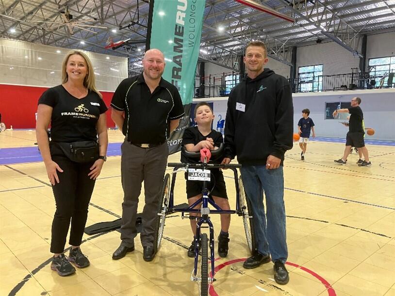 David Wilson from EnergyAustralia and members of the Frame Running team with a participant using the custom-designed three-wheel bicycle, and a young participant demonstrating it in action.